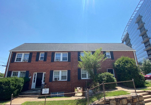 a red brick house with a tall building behind it
